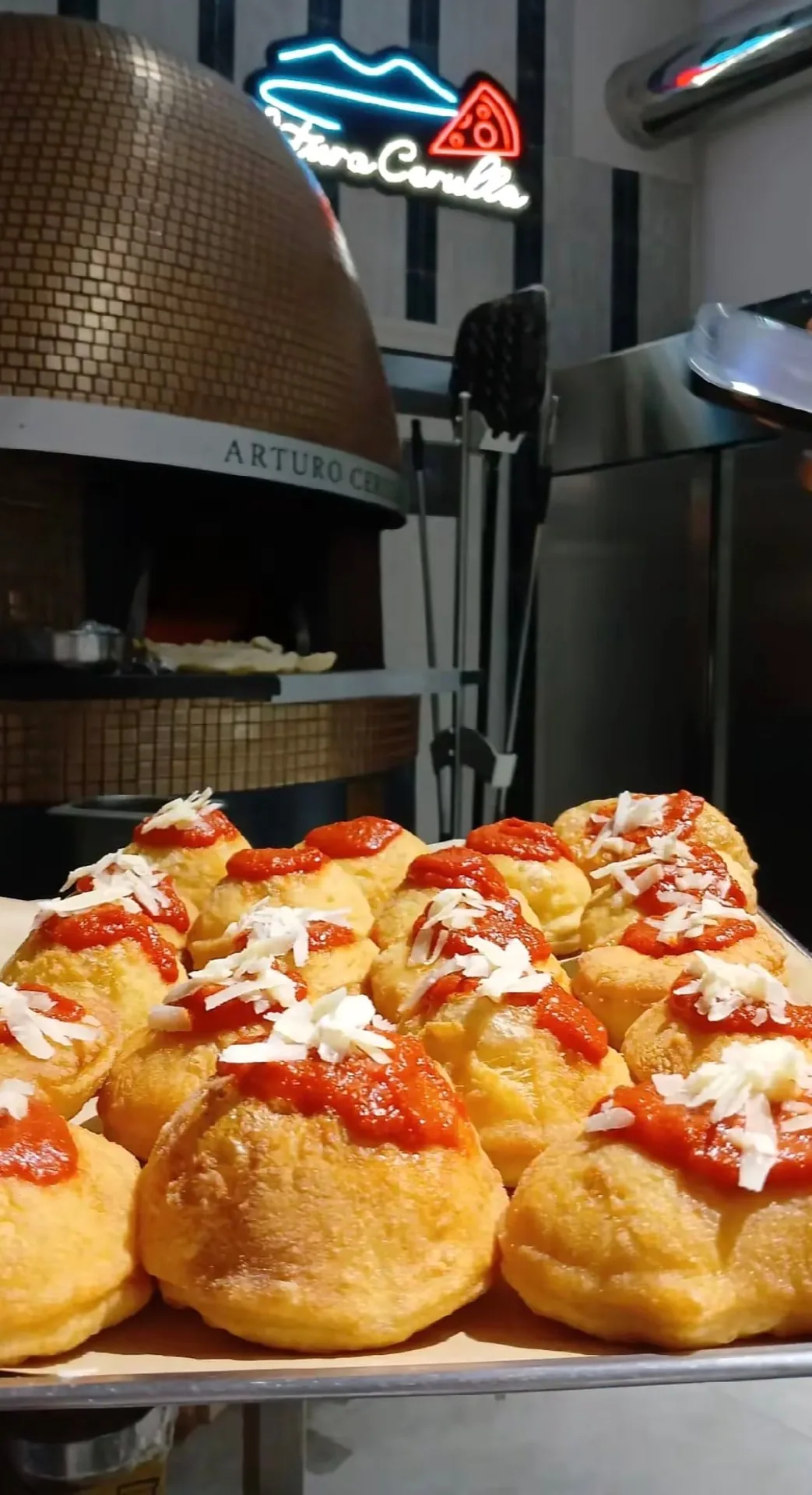 Montanarine fritte con pomodoro e parmigiano davanti al forno a legna